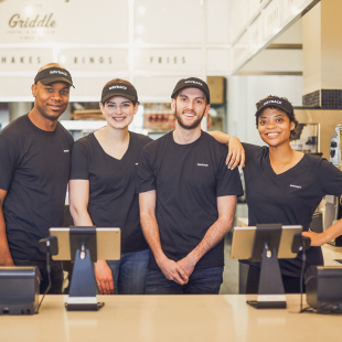 4 wayback employees posing behind a counter